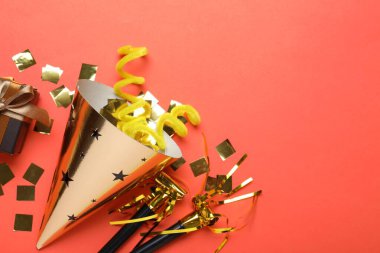 Güzel bir parti şapkası ve kırmızı arka planda diğer şenlikli dekorlar, düz yatış. Metin için boşluk