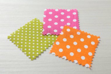 Beyaz ahşap masadaki farklı kumaşlardan örnekler, yakın plan.