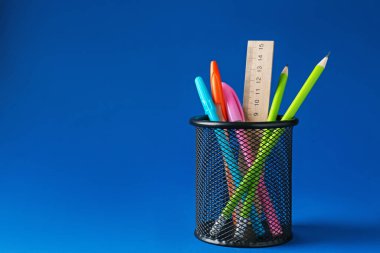 Koyu mavi arka planda kalem tutacağında farklı bir kırtasiye malzemesi. Metin için boşluk