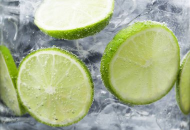 Koyu arkaplanda limon dilimleri ve buzla soda tazeleniyor. Yakın plan.