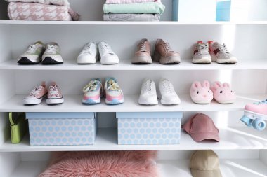 Farklı ayakkabılar, aksesuarlar ve içeride raflarda duran kıyafetler. Ayakkabı deposu