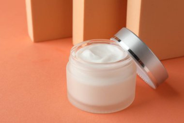 Turuncu arka plandaki kavanozda nemlendirici vücut kremi sunumu, yakın plan. Metin için boşluk