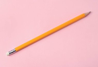 Pembe arka planda keskin bir grafit kalem, üst görünüm.