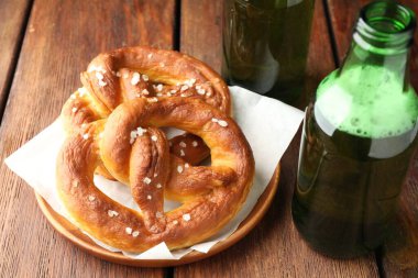 Lezzetli krakerler ve bira şişeleri ahşap masada, yakın plan.