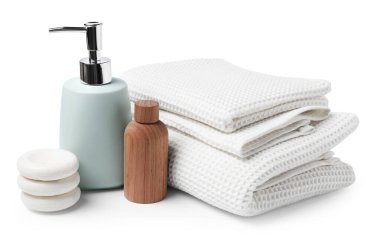 Temiz waffle havluları, kozmetik ürünleri ve beyaza izole edilmiş spa taşları.