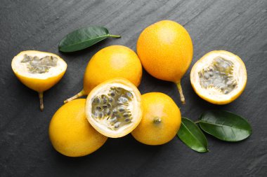 Olgun tutku meyveleri ve yeşil yapraklar siyah masanın üzerinde, düz yatıyordu.