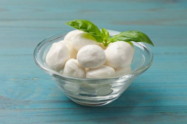 Mozzarella peynir topları ve fesleğen mavi ahşap masada, yakın plan.