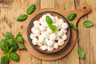 Mozzarella peyniri topları ve fesleğen ahşap masada, düz yatıyordu.