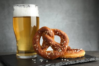 Lezzetli krakerler ve koyu dokulu masada bir bardak bira. Gri arka planda, yakın planda.