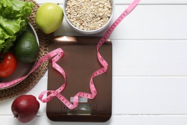 Elektronik mutfak ölçeği, mezura ve beyaz ahşap masa üzerindeki ürünler, düz yatak. Metin için boşluk