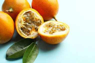 Olgun sarı tutku meyveleri ve açık mavi arka planda yapraklar, yakın plan.