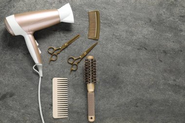 Gri dokulu arka planda farklı saç şekillendirme araçları, düz yatış. Metin için boşluk