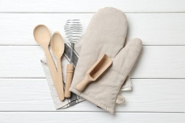 Farklı mutfak aletleri ve fırın eldivenleri beyaz ahşap masa, üst manzara.