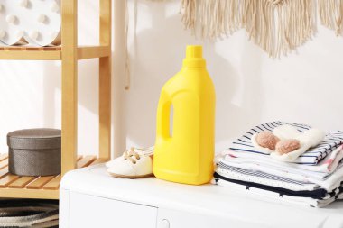 İçerideki çamaşır makinesinde yumuşatıcı ve bebek kıyafetleri olan bir şişe.