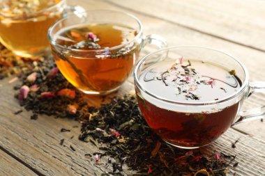 Tahta masada farklı bitki çayları ve kuru yapraklar, yakın plan.