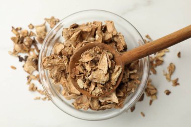 Kuru hindiba kökleri kasede ve kaşıklar beyaz masada, üst tarafta.