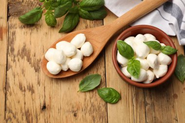 Mozzarella peyniri topları ve fesleğen ahşap masada, düz yatıyordu.