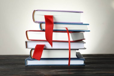 Açık gri arkaplan, yakın plan, ahşap masa üzerinde kırmızı kurdele yer imleri olan kitaplar