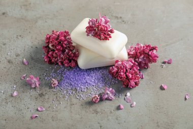 Gri desenli masada sabun, deniz tuzu ve leylak çiçekleri.