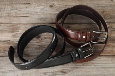 İki deri kemer, ahşap masanın üstünde, manzaranın üstünde.