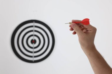 Hedef alınıyor. Oklu bir adam arka planda dart tahtasına nişan alıyor, yakın plan.