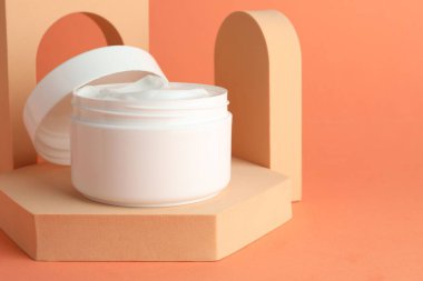 Turuncu arka plandaki kavanozda nemlendirici vücut kremi sunumu, yakın plan. Metin için boşluk