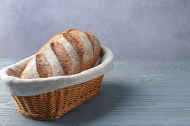 Gri ahşap masada sepette bir somun ekmek. Metin için boşluk