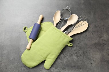 Farklı mutfak aletleri fırın eldivenleri gri masada, düz yatıyordu.