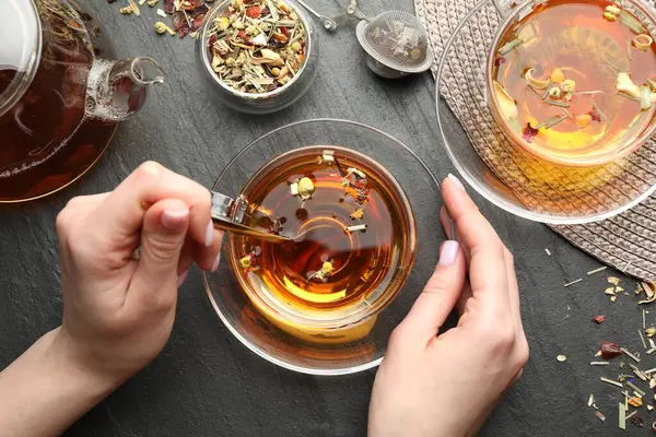 Siyah masada aromatik bitkisel çayı olan bir kadın.