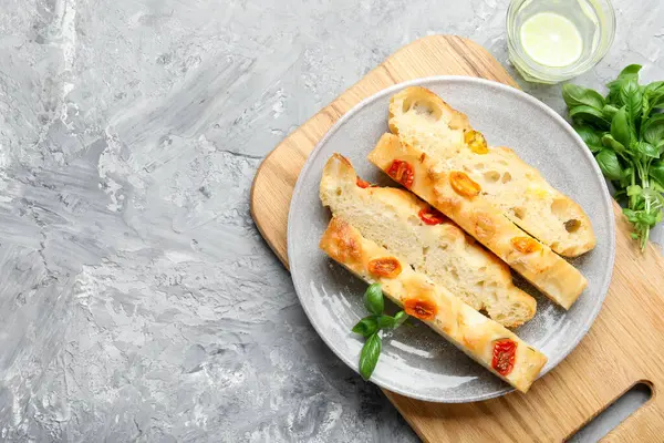 Domatesli, fesleğenli ve bardaklı lezzetli Focaccia parçaları gri desenli masada, düz yatıyordu. Metin için boşluk