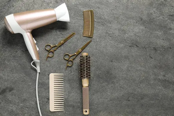 Gri dokulu arka planda farklı saç şekillendirme araçları, düz yatış. Metin için boşluk
