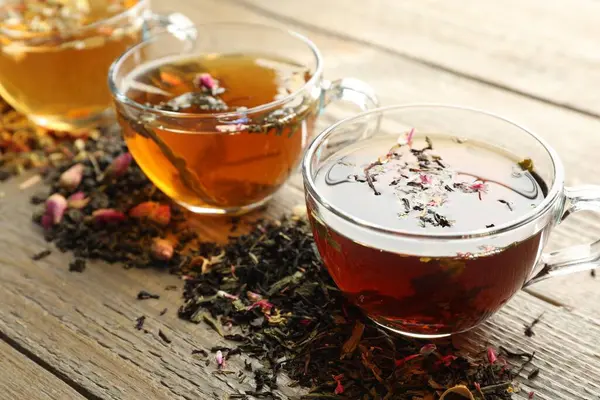 Tahta masada farklı bitki çayları ve kuru yapraklar, yakın plan.