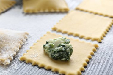 Ahşap masada süzme peynirli ve ıspanaklı ravioli yapmak, yakın plan.