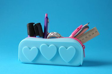 Açık mavi arkaplanda kalem kutusunda farklı bir kırtasiye, yakın plan