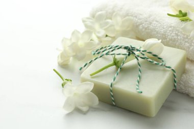 Bir kalıp sabun, yasemin çiçekleri ve beyaz mermer masaya havlu, yakın plan. Metin için boşluk