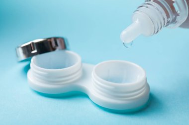 Kontakt lens solüsyonu açık mavi arkaplanda, yakın plan