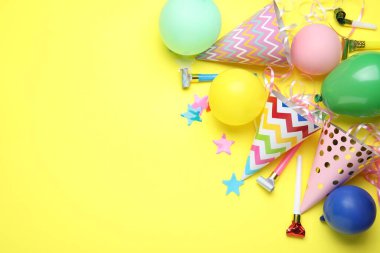 Güzel parti şapkaları ve sarı arka planda diğer şenlikli dekorlar, düz yatış. Metin için boşluk