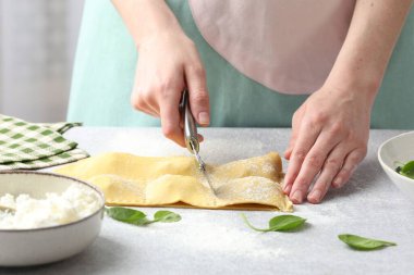 Işık masasında ravioli kesen kadın, yakın plan.