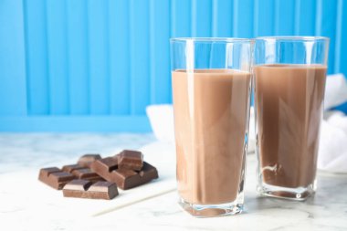 Bardakta çikolatalı süt ve beyaz mermer masada malzeme, yakın plan.