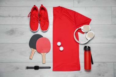 Spor kıyafetleri ve yerde kulaklıkları olan düz bir kompozisyon.