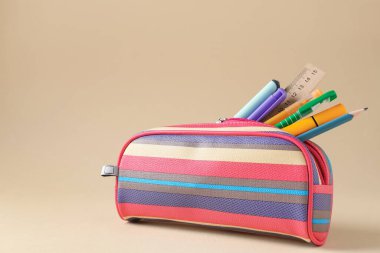 Bej arka planda kalem kutusunda farklı bir kırtasiye malzemesi. Metin için boşluk