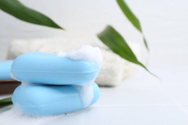 Beyaz masadaki köpüklü sabun çubukları, yakın plan. Metin için boşluk