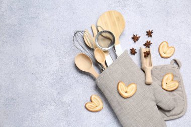 Farklı mutfak aletleri fırın eldivenlerinde, kurabiyeler ve anason yıldızları ışık masasında, düz yerde. Metin için boşluk