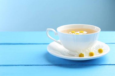 Fincanda nefis papatya çayı ve açık mavi ahşap masada taze çiçekler, yakın plan. Metin için boşluk