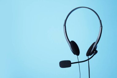 Açık mavi arkaplanda mikrofonlu kulaklık, metin için boşluk