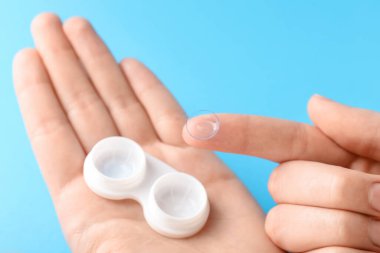 Açık mavi arka planda kontak lensli kadın, yakın plan