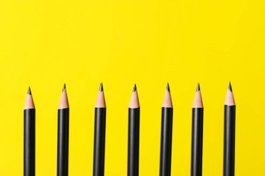 Sarı arka planda bir sürü keskin grafit kalem, yakın plan. Metin için boşluk