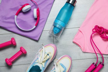 Spor ayakkabıları, spor ayakkabıları, ip atlama, su şişesi, kulaklıklar ve dambıllar yere.