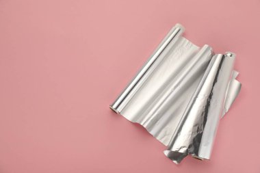 Pembe arka planda alüminyum folyo ruloları, üst manzara. Metin için boşluk