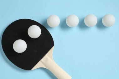 Masa tenisi raketi ve toplar açık mavi arkaplanda, düz yatıyordu